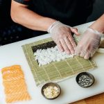 person making sushi roll